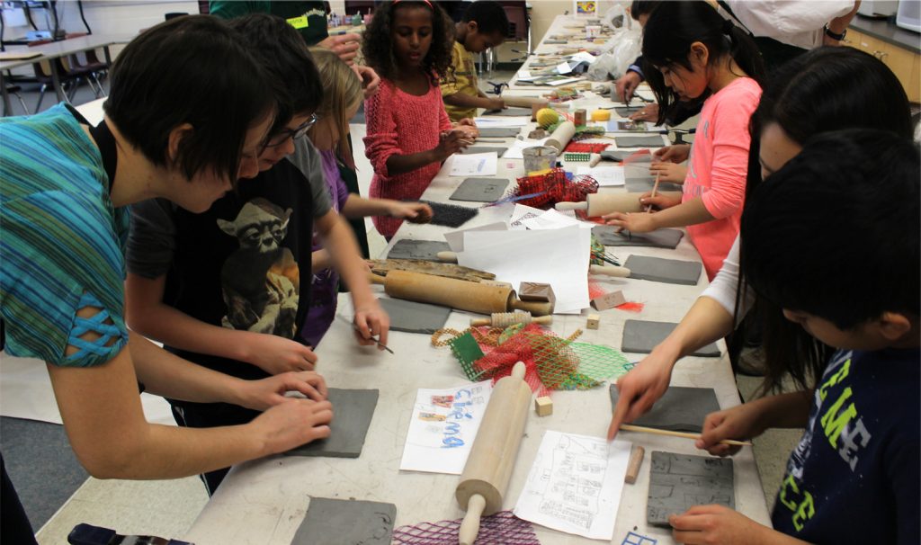Artist Alexandra Iorgu working with a group of students using clay.